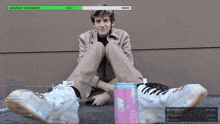 a man sits on the ground next to a can that says " the pu "