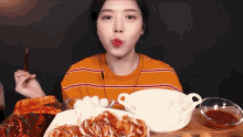 a woman is eating a variety of food with chopsticks and a bowl of rice