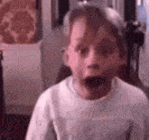 a young boy is making a surprised face with his mouth open .