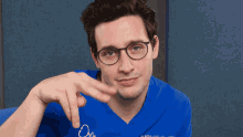 a man wearing glasses and a blue shirt with the letter o on it