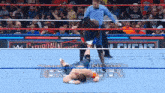 a wrestler is laying on the floor in a wrestling ring while a referee watches