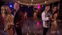 a group of people are dancing in front of a sign that says aew live
