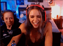 two women wearing headphones are laughing in front of a shure microphone ..