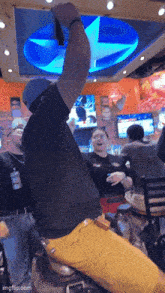 a man in a black shirt is sitting on a horse with his arm in the air