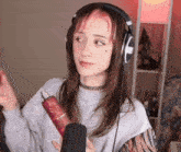 a woman wearing headphones and holding a microphone is standing in front of a microphone .