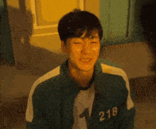 a man is wearing a green jacket with the number 218 on it