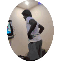 a man in a white shirt and grey shorts is standing in front of a television