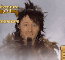a man with feathers on his head is smiling in front of an adventure call sign