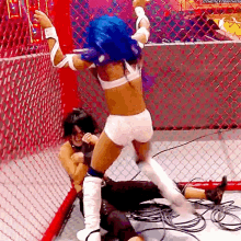 a woman with blue hair is wrestling another woman in a cage