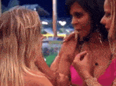 a woman in a pink bikini is talking to another woman