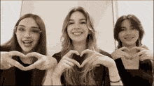 three girls make a heart shape with their hands