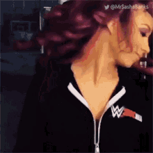 a woman with red hair is wearing a black sweatshirt with a w logo on it .
