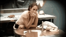 a woman sits at a table with her hands on her face