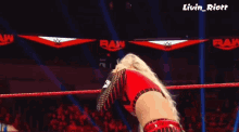 a woman in a red top is standing in a wrestling ring with a crowd watching .
