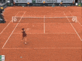 a woman is walking on a tennis court in front of a emirates sign