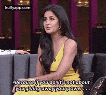 a woman in a yellow dress is sitting on a couch talking to another woman .