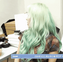 a woman with green hair is sitting in front of a table with the name dami on the bottom
