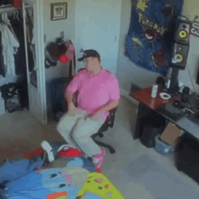 a man in a pink shirt dancing in front of a pokemon tapestry