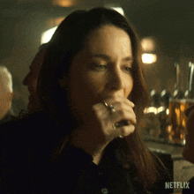 a woman with a ring on her finger is drinking a beer from a glass ..