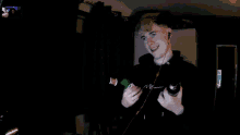 a man in a black hoodie holds two bottles of beer in his hands