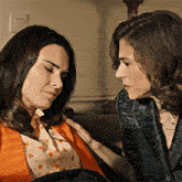 two women are looking at each other with one wearing a black jacket