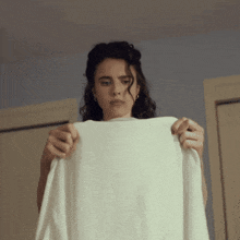 a woman is holding a white shirt in her hand