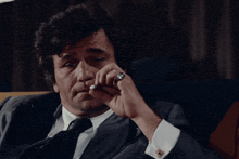 a man in a suit and tie is sitting on a couch with his eyes closed