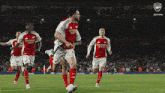 a group of soccer players wearing red jerseys that say emirates fly emirates
