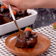 a person is holding a fork over a piece of chocolate cake