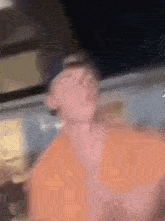 a blurry picture of a man in an orange shirt and hat
