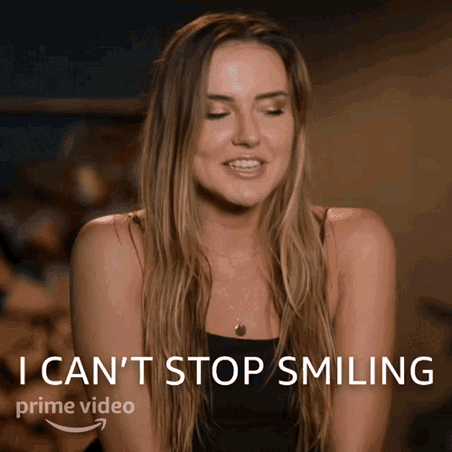 a woman is smiling in front of a sign that says i can 't stop smiling prime video