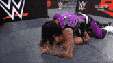 a woman in a purple shirt is laying on a man 's lap