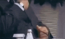 a man in a suit and tie is smoking a cigarette while sitting at a table .
