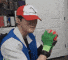 a man wearing a hat and gloves is holding a pokemon ball .