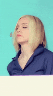a woman with blonde hair wearing a blue shirt looks down