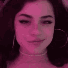 a close up of a woman 's face with a pink background and a pink light behind her .