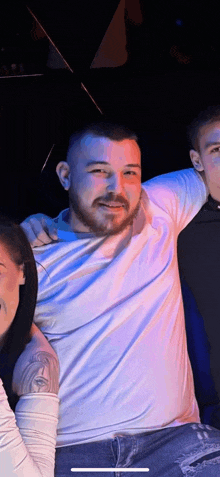 a man with a beard and a tattoo on his arm is posing for a picture with a woman .