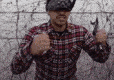 a man wearing a plaid shirt and a helmet is holding a pair of scissors in his hands .