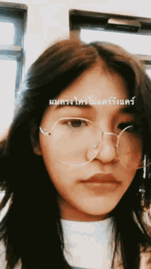a girl wearing glasses and a white shirt has a foreign language written on her face