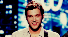 a man is smiling while holding a guitar in front of a sign that says ' u '