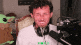 a man wearing headphones is sitting in front of a microphone with a stuffed animal in the background that says emma