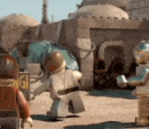 a group of lego figures are standing in front of a building in a desert .