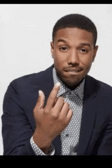 a man in a suit and tie is making a funny face and giving the middle finger .