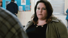 a woman is standing in front of a man in a room and looking at him .