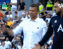 a man in a white shirt with the letter a on it shakes another man 's hand