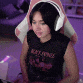 a woman wearing headphones and a black shirt that says " black stones "