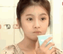 a young girl is holding a cup in her hand and looking at the camera