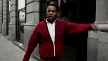 a man in a red jacket is standing on a sidewalk