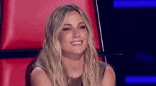a woman is sitting in a red chair smiling .