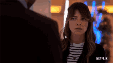 a woman in a striped shirt is standing next to a man in a suit and the word netflix is on the bottom right